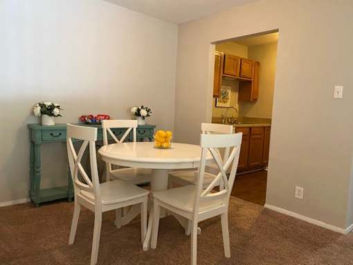 A dining room with a white table and chairs.