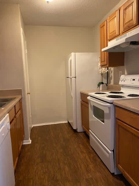 A kitchen with a white fridge, white oven, and white stove.