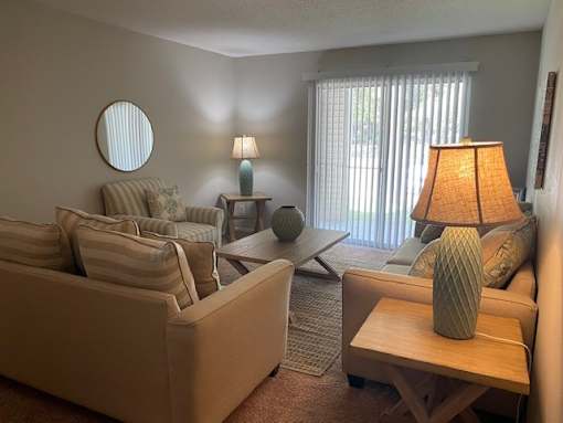 A living room with a tan couch, a wooden table, and a lamp.