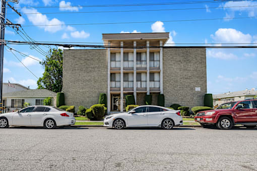 Three cars are parked in front of a building.
