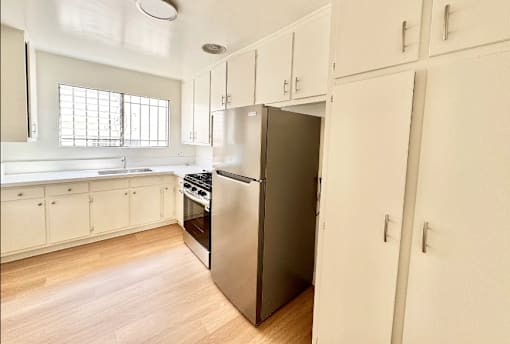 A kitchen with a refrigerator, oven, and cabinets.