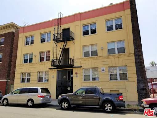 a large yellow building with two cars parked in front of it
