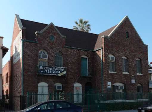 A brick building with a sign that says "Now Selling" and a phone number.