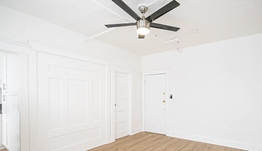 A room with a ceiling fan and two doors.