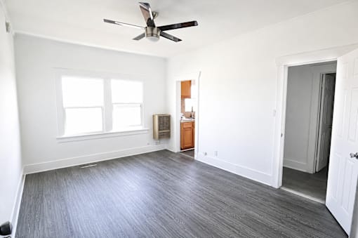 A room with a ceiling fan and a door.