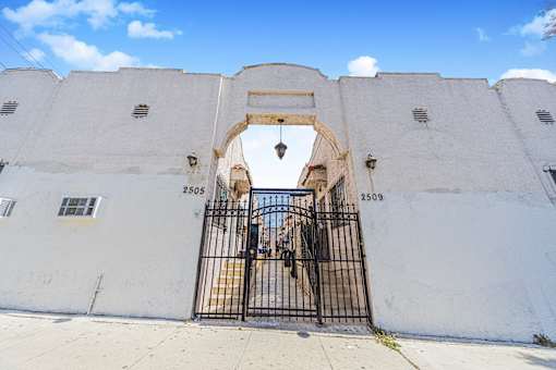 A white wall with a black gate and numbers 2505 and 2509 on it.