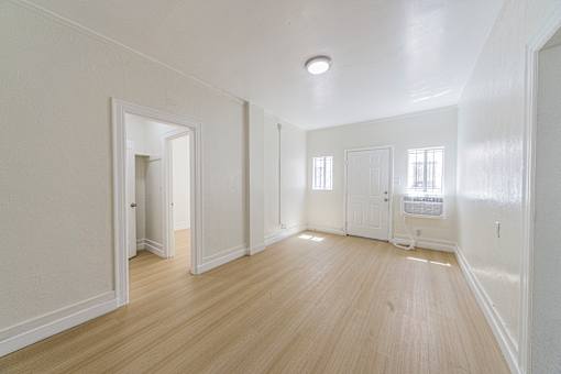A large empty room with wooden floors and white walls.