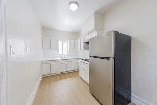 A kitchen with a black refrigerator and white cabinets.