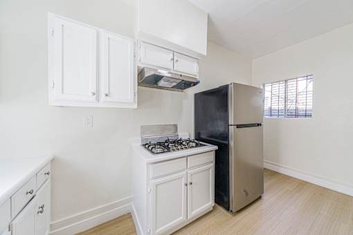 A kitchen with white cabinets and a black refrigerator.