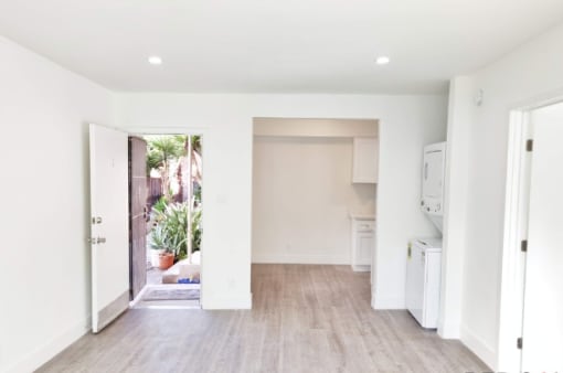 an empty living room with a door to a kitchen
