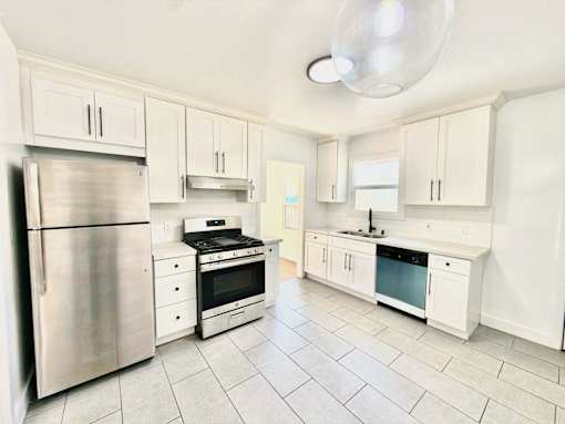 A kitchen with white cabinets and a stainless steel refrigerator.