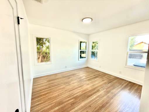 A room with wooden flooring and white walls.