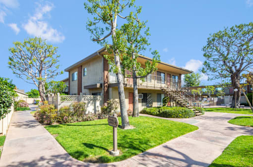 a house with a sidewalk and trees in front of it