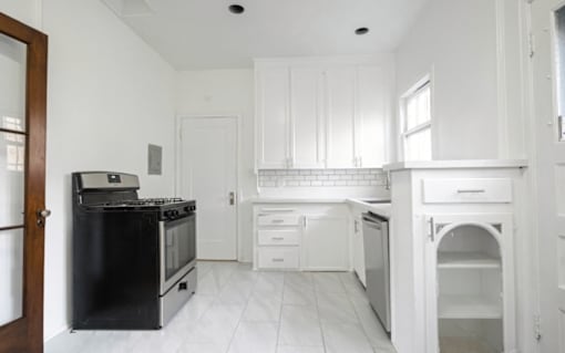 A kitchen with white cabinets and a black stove top oven.