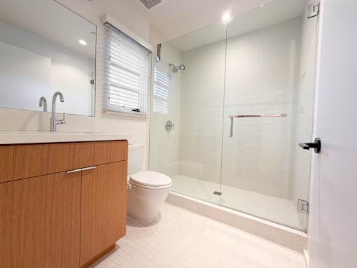 A modern bathroom with a toilet, sink, and walk-in shower.