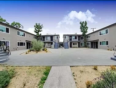 an empty parking lot in front of several apartment buildings