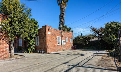 an old brick building on a street with a palm tree