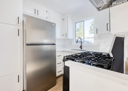 A modern kitchen with a stainless steel refrigerator and a black stove top.