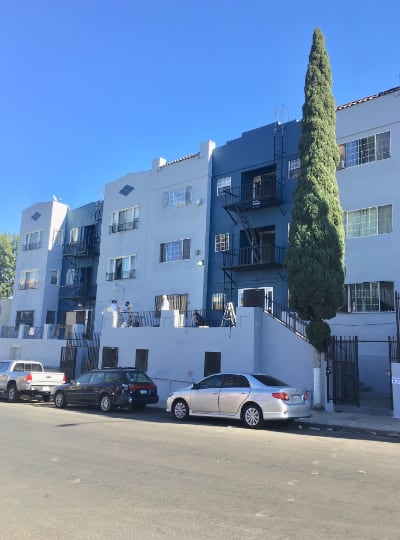 the side of a white building with cars parked in front