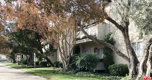 a white house with trees and bushes in front of it
