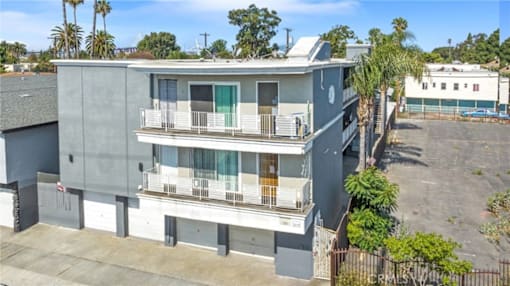 A grey two-story apartment building with a balcony on the second floor.