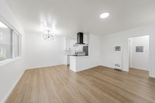 A spacious kitchen with a wooden floor and white walls.