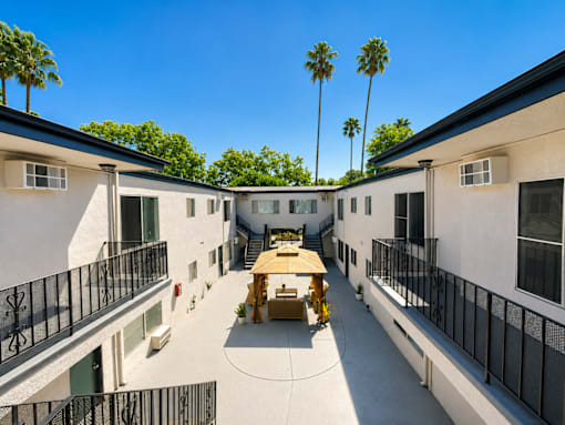 A courtyard surrounded by buildings with a table and chairs in the middle.