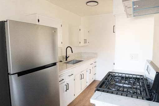 A kitchen with a stainless steel refrigerator and a black and white stove top.