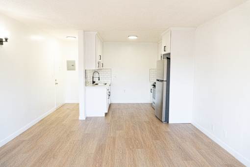 A kitchen with a refrigerator, sink, and cabinets.