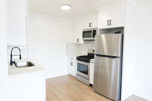 A modern kitchen with a stainless steel refrigerator, microwave, oven, and sink.