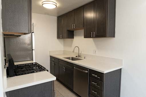A kitchen with dark brown cabinets and white countertops.