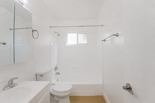 A white bathroom with a toilet, sink, and shower.