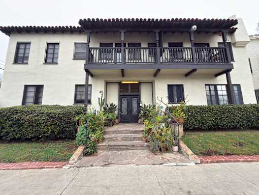A white house with a black door and a balcony.