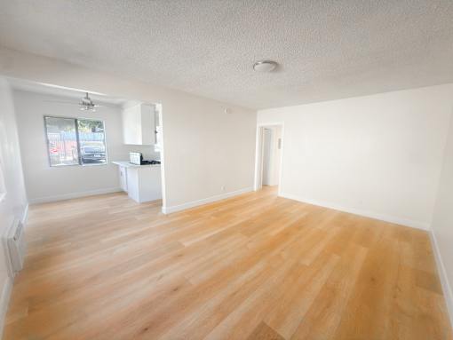 A room with wooden flooring and white walls.