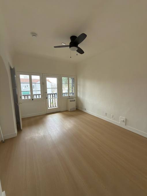 A room with a ceiling fan and wooden flooring.