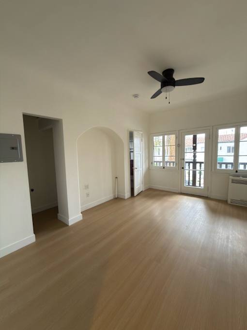A room with a ceiling fan and wooden flooring.