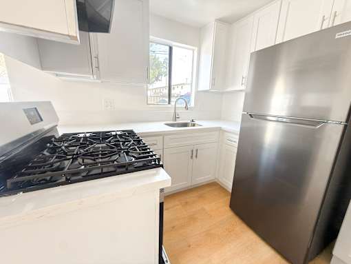 A kitchen with a stove, sink, and refrigerator.