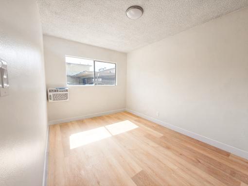 A room with a window and wooden flooring.