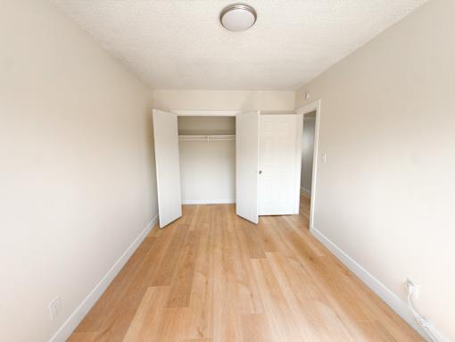 A long hallway with a light on the ceiling and a door at the end.