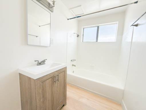 A white sink with a wooden cabinet below it.