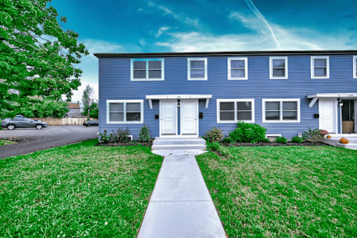 a blue house with a lawn and sidewalk in front of it