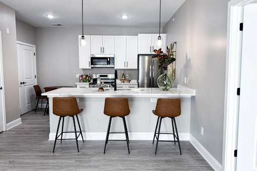 A kitchen with a white island and brown barstools.