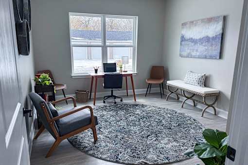 A room with a chair, a table, and a rug.