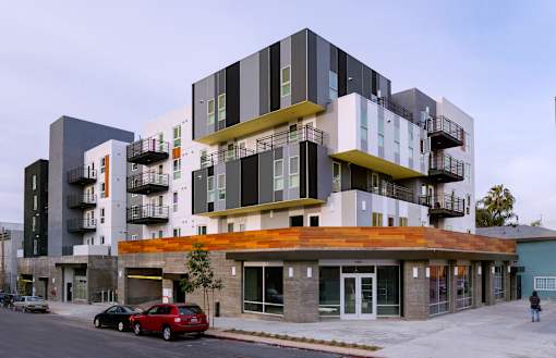 A modern multi-story building with balconies and a wooden front.