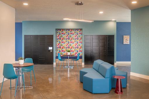 A room with blue chairs and a table with a plant on it.