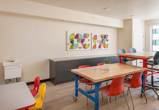 A room with a table and chairs and a painting on the wall.