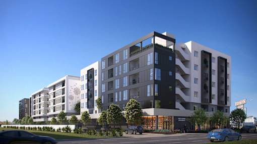 A modern multi-story residential building with balconies and a parking lot in front.