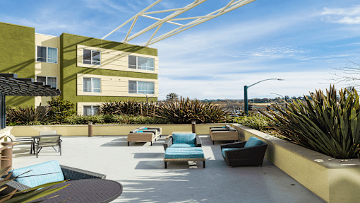 a patio with chairs and tables and a building in the background