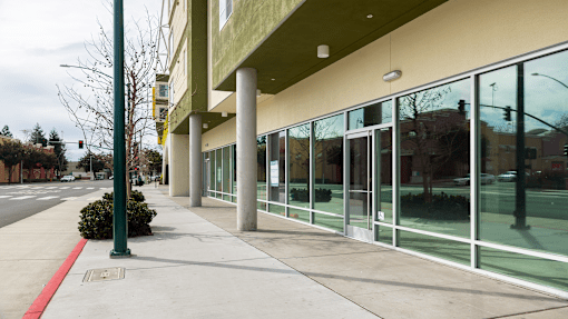 the outside of a building with glass windows and a sidewalk