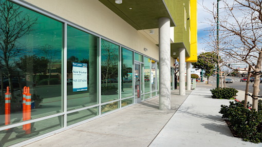 the front of a building with glass windows and a sidewalk
